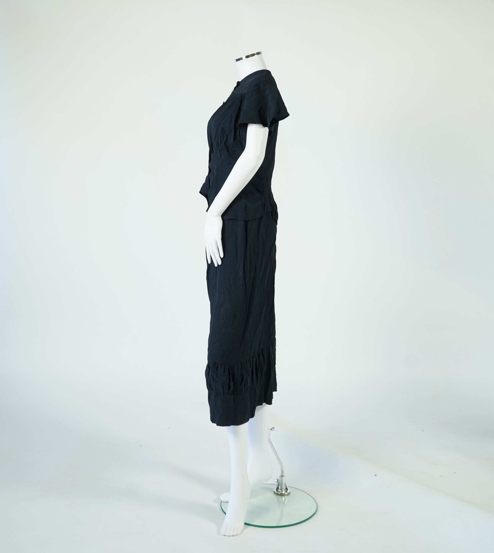 A 1920’s light green silk evening cape with hand batik borders and label: Tito de Canival Mode, together with a navy ladies two piece suit and a maroon satin evening dress. Cape 100cm long. Condition - cape good, navy tw